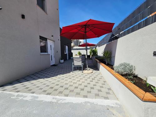 a patio with a chair and a red umbrella at Apartments Anamarija in Zadar