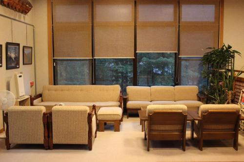 a waiting room with couches and chairs and windows at Ryokan Tanaka in Takayama