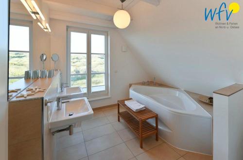 a bathroom with a large tub and two sinks and a tub at Landhaus Ostdüne Ferienwohnung Dünenmeer in Juist