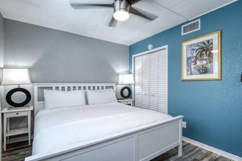 a bedroom with a white bed and a blue wall at Sunset Beach Suites at Madeira Beach! Steps to Beach & Restaurants! - Suite 6 in St Pete Beach