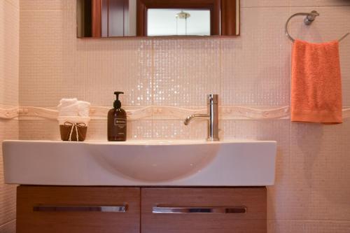 a white sink in a bathroom with a mirror at Kiki’s 3BD apt. with Citrus Garden & BBQ in Gastoúni