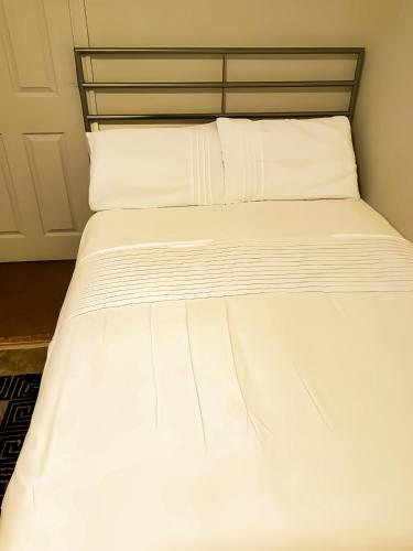 een wit bed met witte lakens en kussens bij Urban Oasis Loft in Bradford