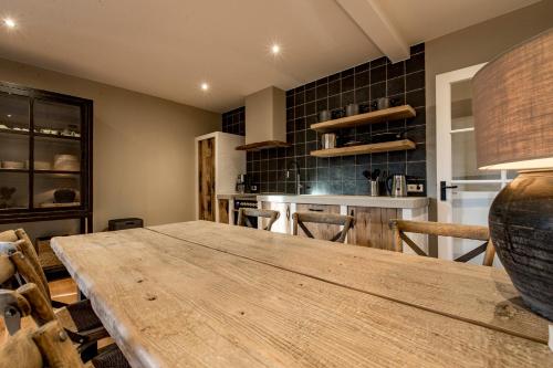 a dining room with a wooden table and a kitchen at Wien's Villa Veluwe in Hoenderloo