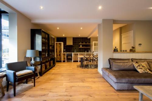 a living room with a couch and a kitchen at Wien's Villa Veluwe in Hoenderloo