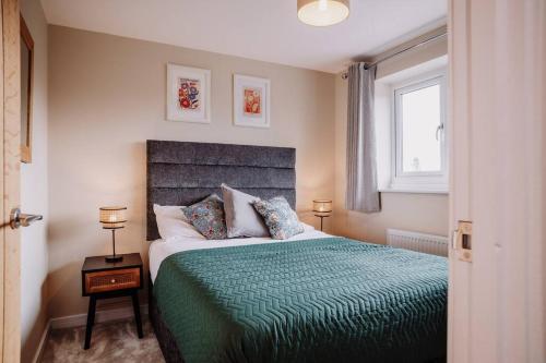 1 dormitorio con 1 cama con edredón verde y ventana en Modern Home in Warwickshire, en Stratford-upon-Avon