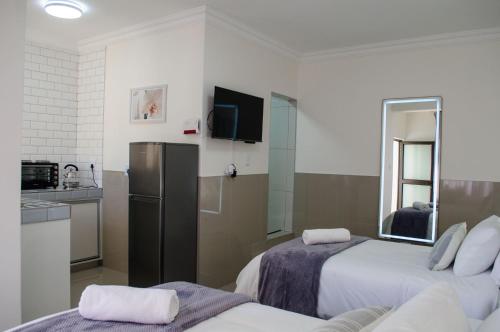 a room with two beds and a kitchen with a refrigerator at Shark Island Guesthouse in Lüderitz