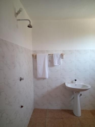 a bathroom with a sink and a shower with towels at Gemini Villas in Kijiwetanga