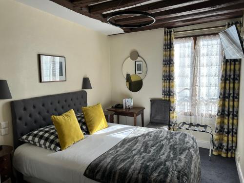 ein Schlafzimmer mit einem großen Bett mit gelben Kissen in der Unterkunft Hotel du Dragon in Paris