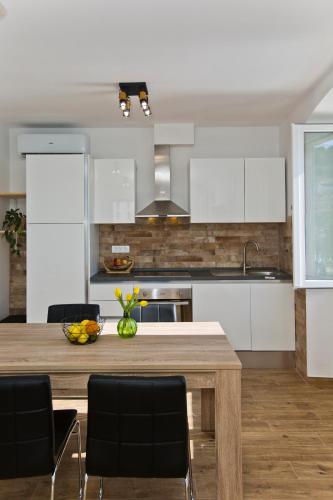 a kitchen with white cabinets and a wooden table at Hvar sea view apartment in Hvar