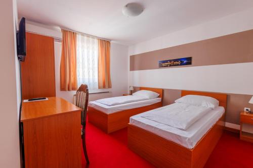 um quarto de hotel com duas camas e uma secretária em Pansion Strossmayer em Osijek