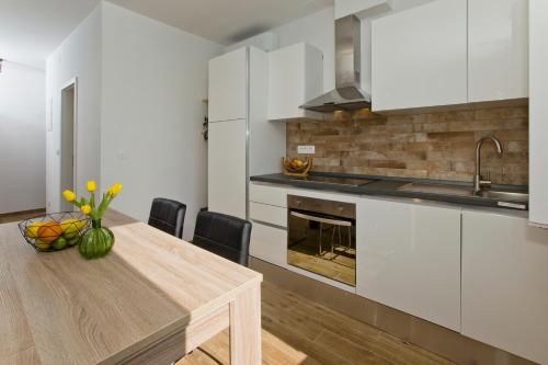 a kitchen with white cabinets and a wooden table at Hvar sea view apartment in Hvar