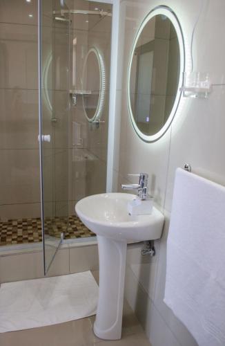 a bathroom with a sink and a shower with a mirror at Shark Island Guesthouse in Lüderitz