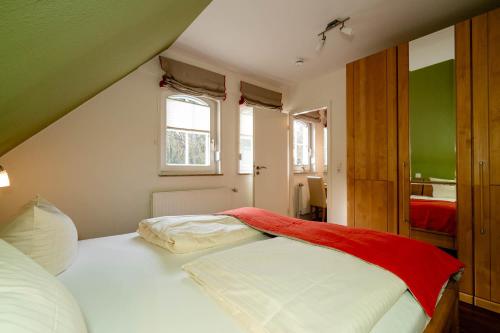 um quarto com uma cama branca e um cobertor vermelho em Ferienwohnung Südwind em Westerland