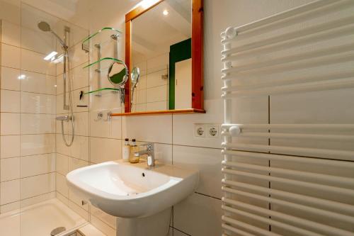 La salle de bains blanche est pourvue d'un lavabo et d'une douche. dans l'établissement Ferienwohnung Südwind, à Westerland