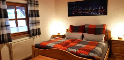 a bedroom with a bed with an orange and gray blanket at Ferienhaus Breit in Eppenschlag