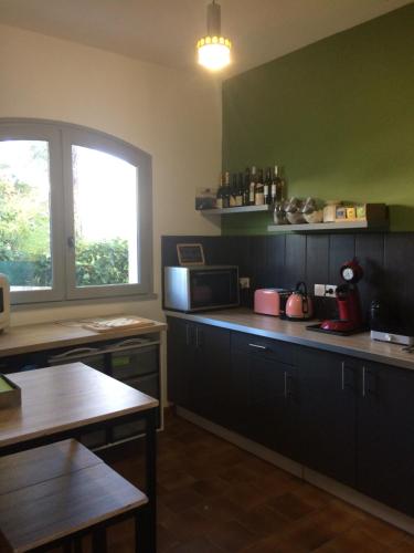 una cocina con armarios negros y una ventana en Maison d'hôtes naturiste Villa PaulAna, en Cap d'Agde