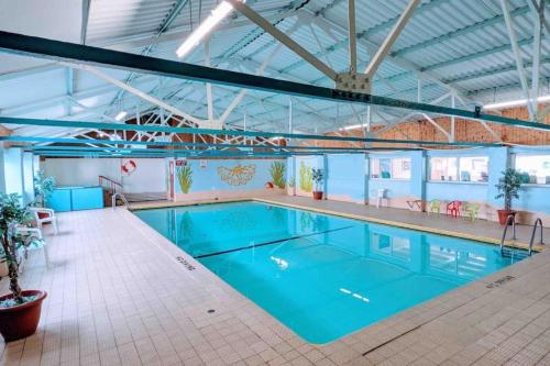 a large swimming pool with blue water in a building at Ocean Breeze, Gower Holiday Village. Allows Dogs in Swansea