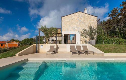 een zwembad met twee stoelen en een huis bij Villa-Veritas in Višnjan