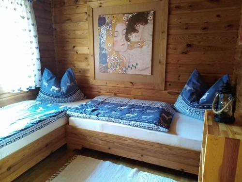 2 Betten in einem Holzzimmer mit blauen Kissen in der Unterkunft Ferienhaus Kumpitsch in Sankt Johann im Saggautal