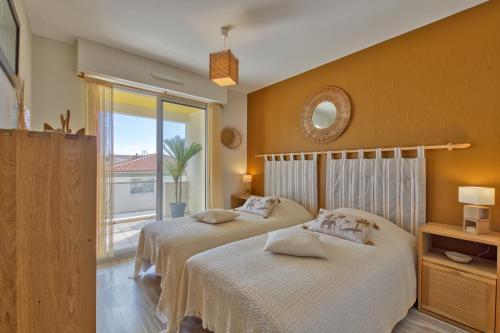 une chambre avec deux lits et un balcon dans l'établissement Le Sable Fin - Appt à 300m de la plage, à Royan