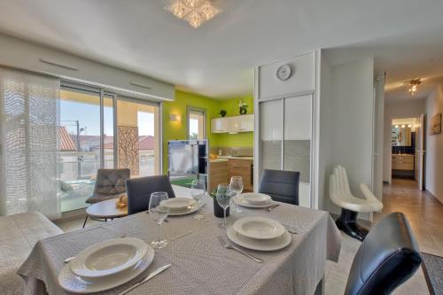 une salle à manger avec une table avec des assiettes et des verres à vin dans l'établissement Le Sable Fin - Appt à 300m de la plage, à Royan