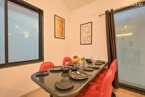 uma sala de jantar com uma mesa e cadeiras vermelhas em EKOSTAY - Eclipse Villa em Karjat