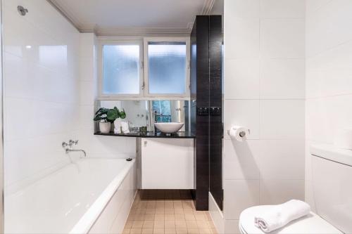een witte badkamer met een bad en een wastafel bij Coolullah Charm - Your Cosy South Yarra Stay in Melbourne