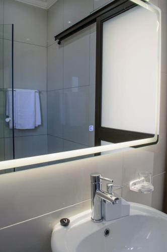 a bathroom with a sink with a mirror and a mirror at Shark Island Guesthouse in Lüderitz