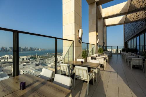 einen Balkon mit Tischen und Stühlen auf einem Gebäude in der Unterkunft Park Hyatt Doha in Doha