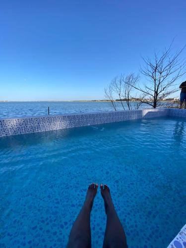 a person laying in a swimming pool next to the water at Hotel le Trarza in Niaga