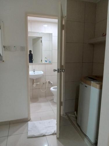 a bathroom with a toilet and a sink and a mirror at PD Corus myHoliday Homes & Apartments in Port Dickson
