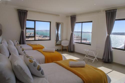 a hotel room with three beds and a view of the water at Shark Island Guesthouse in Lüderitz