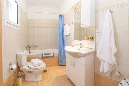 a white bathroom with a toilet and a sink at Kazarma Apartments at Klismata village in Klísmata