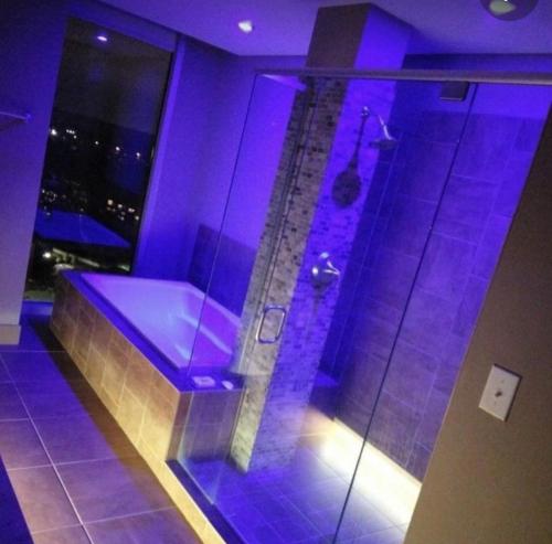 baño con ducha con iluminación púrpura en فندق السعاده, en ‘Izbat Hud.hud