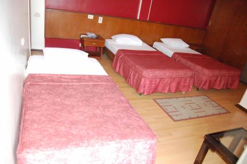 3 camas en una habitación de hotel con colchas rojas en King Hotel Cairo en El Cairo