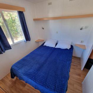 a blue bed in a room with a window at MOBILE HOME COSY 4/5 personnes in Hyères