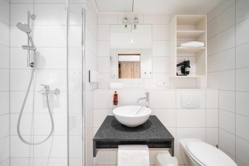 a white bathroom with a sink and a shower at Snooze Apartments in Holzkirchen