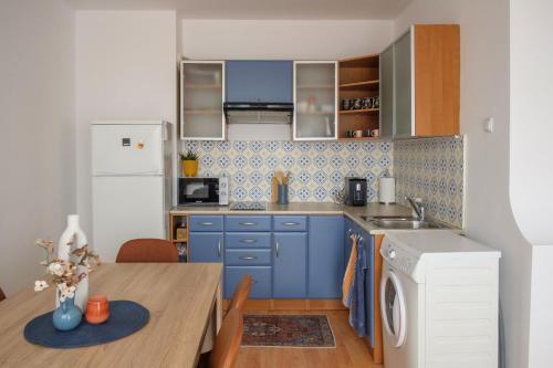 uma cozinha com armários azuis e uma mesa de madeira em Апартамент за гости Бажолета - светъл и уютен дом в сърцето на Ямбол em Yambol