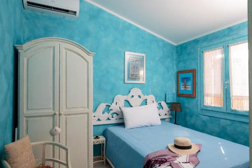 een blauwe slaapkamer met een bed met een hoed erop bij Casa delle Mimose by Wonderful Italy in Badesi