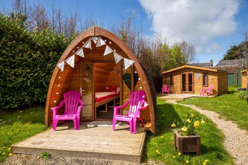 a gazebo with two pink chairs and a house at Podumna Glamping Village in Portumna
