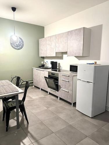une cuisine avec une table et un réfrigérateur blanc dans l'établissement F3 spacieux au centre ville, à Saint-Étienne