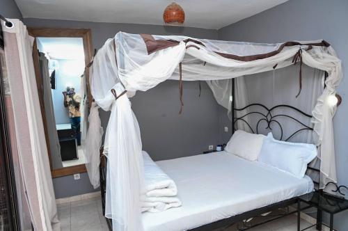 a bedroom with a canopy bed with white sheets at Hotel le Trarza in Niaga
