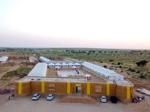 Royal Luxury Camp Jaisalmer في جيلسامر: اطلالة جوية على مبنى كبير فيه سيارات متوقفة