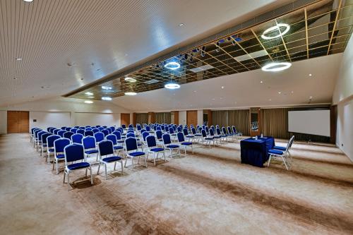 a large room with blue chairs and a screen at Antarim Express in Bharuch