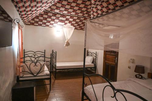 a bedroom with two beds and a canopy bed at Hotel le Trarza in Niaga