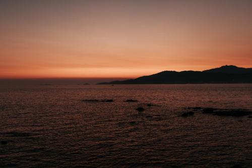 a sunset over the ocean with mountains in the background at Sofitel Golfe d'Ajaccio Thalassa Sea & Spa in Ajaccio