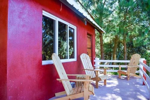 two chairs sitting on the porch of a red house at Finca Chuchiyá cabañas Tecpan in Tecpán Guatemala