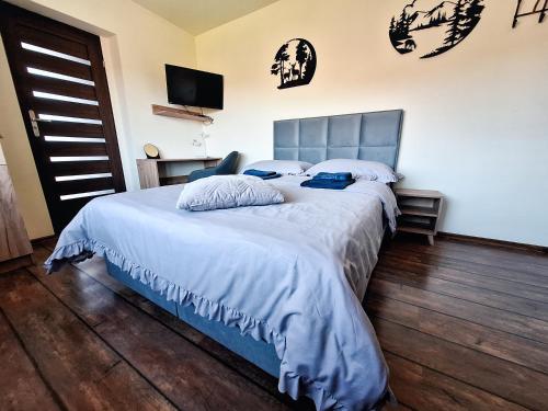 a bedroom with a bed with white sheets and blue pillows at Noclegi Fregata - Pokoje Gościnne w Solinie 661-459-339 in Solina