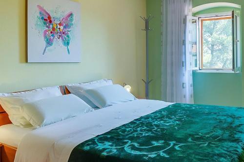 a bedroom with a large bed with a butterfly painting on the wall at House ROSSELLA with cozy apartment and rooms close to the beach in Nerezine