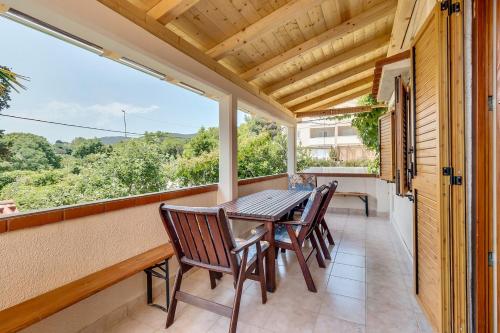 a porch with a table and chairs and a large window at House ROSSELLA with cozy apartment and rooms close to the beach in Nerezine